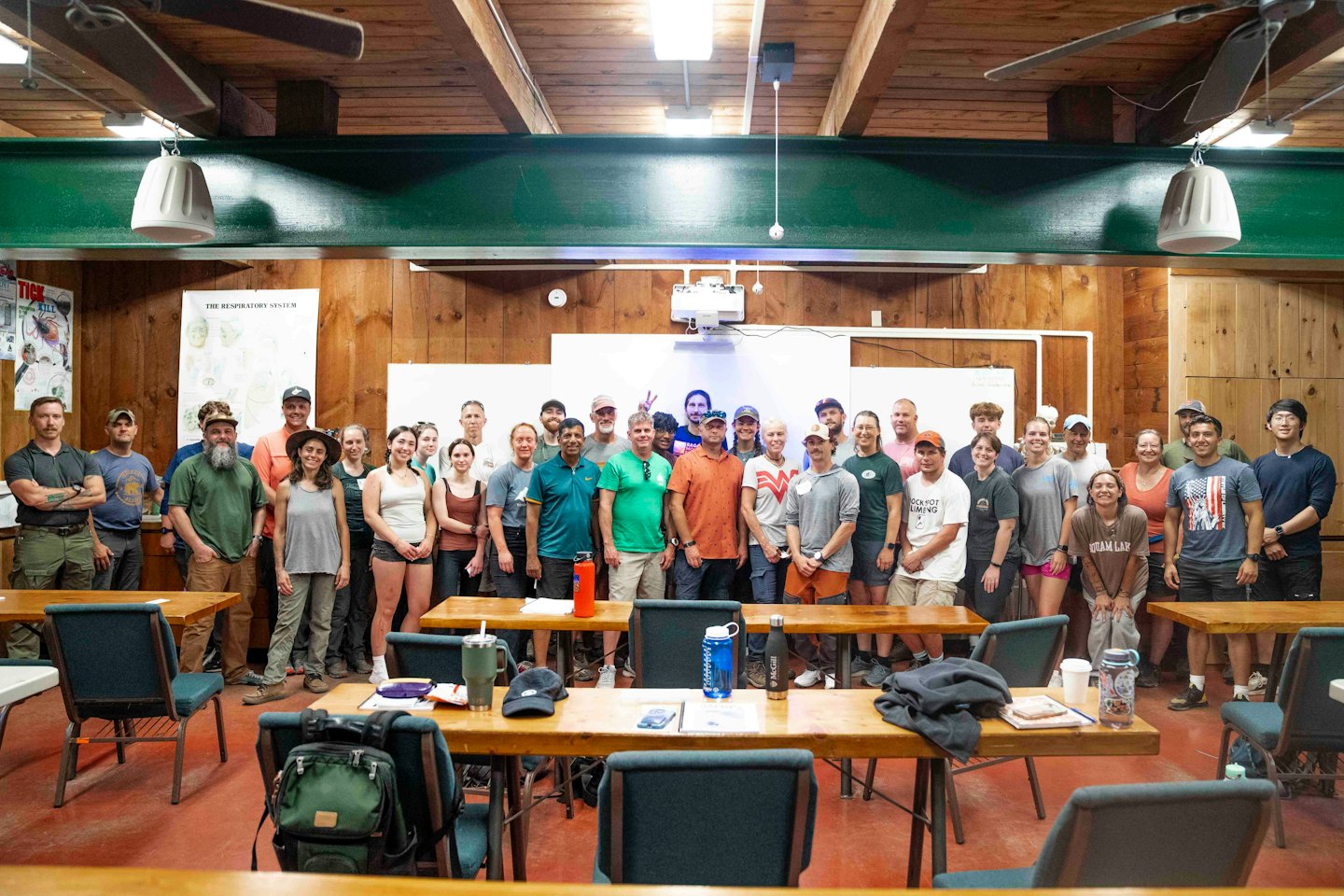 Diverse group of adults smiling in a rustic classroom setting.